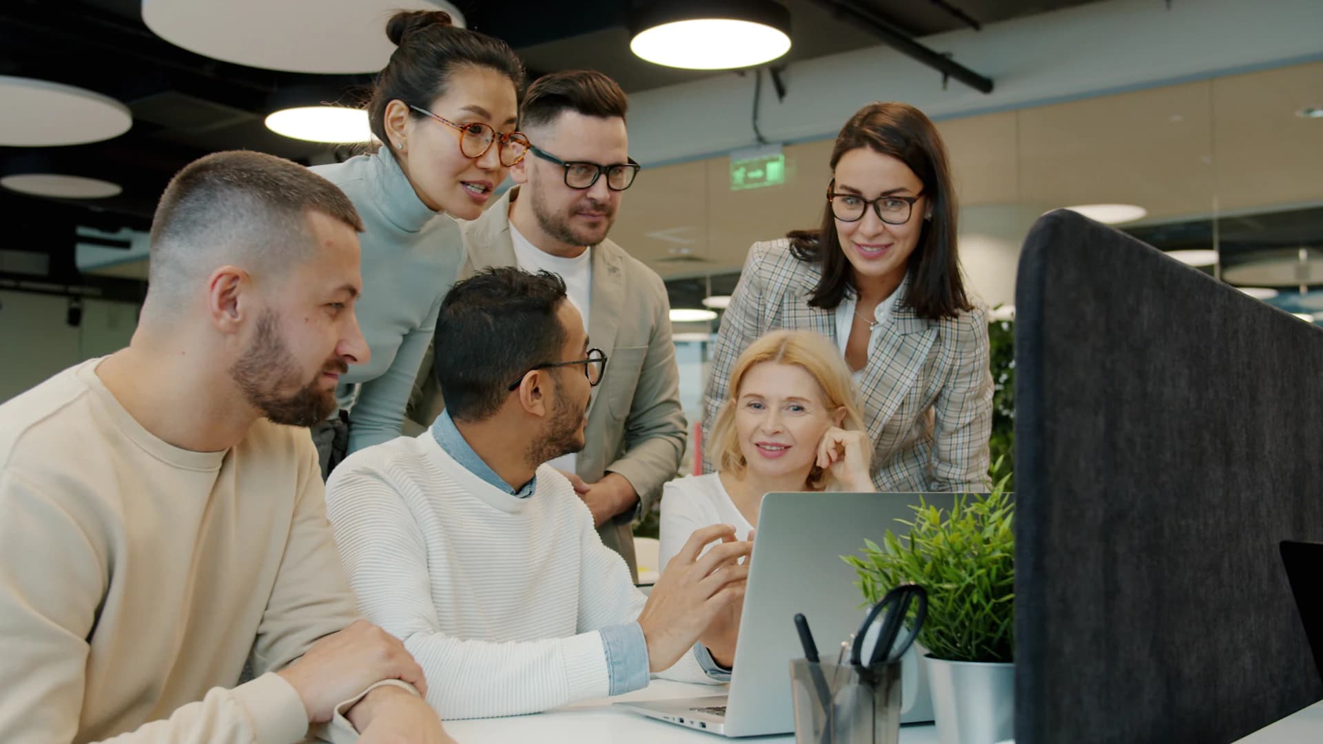 Colleagues gathered around a laptop in an office, working through a prospect list together.
