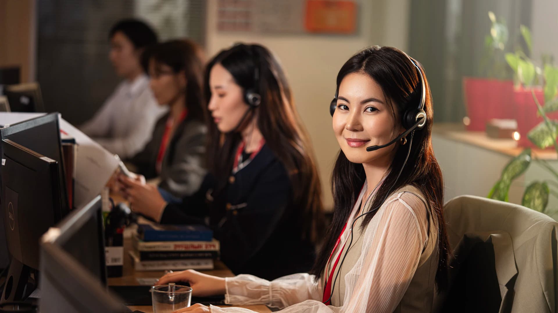 A support agent wearing a headset at a computer, handling a customer conversation.