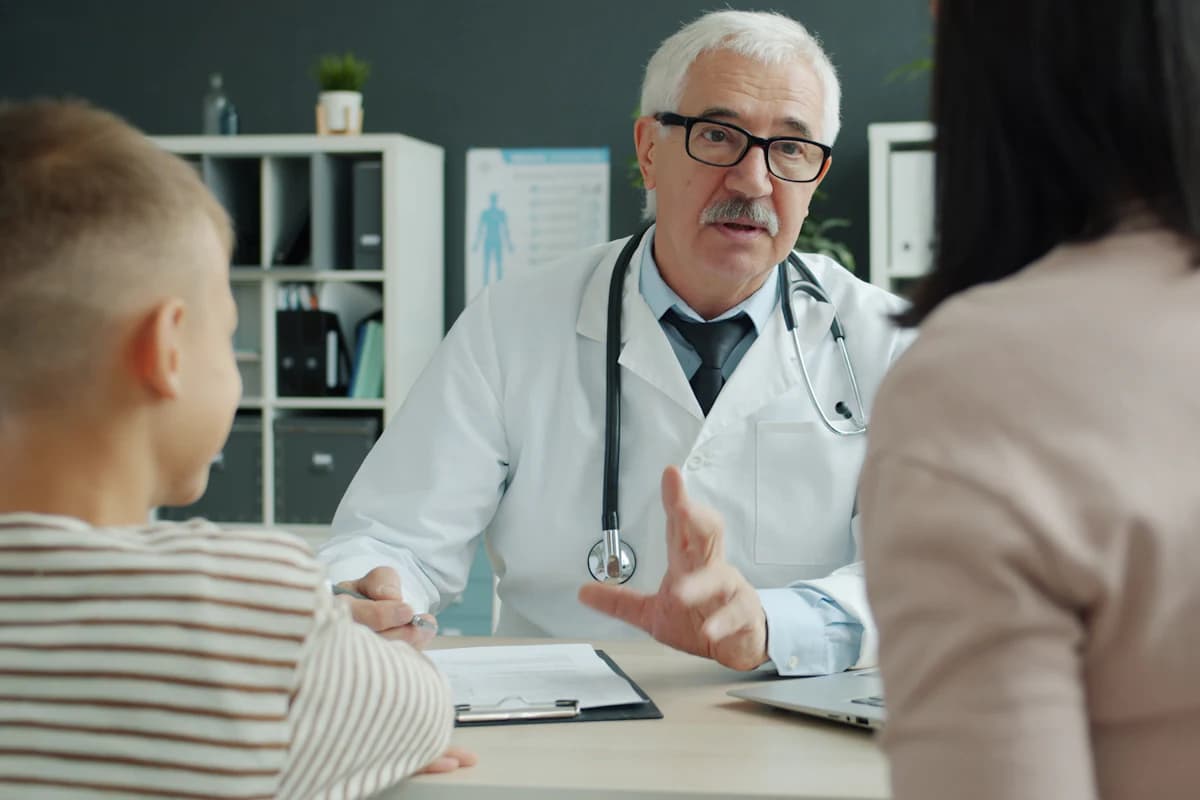 A doctor talking through options with a parent and child in a consulting room.