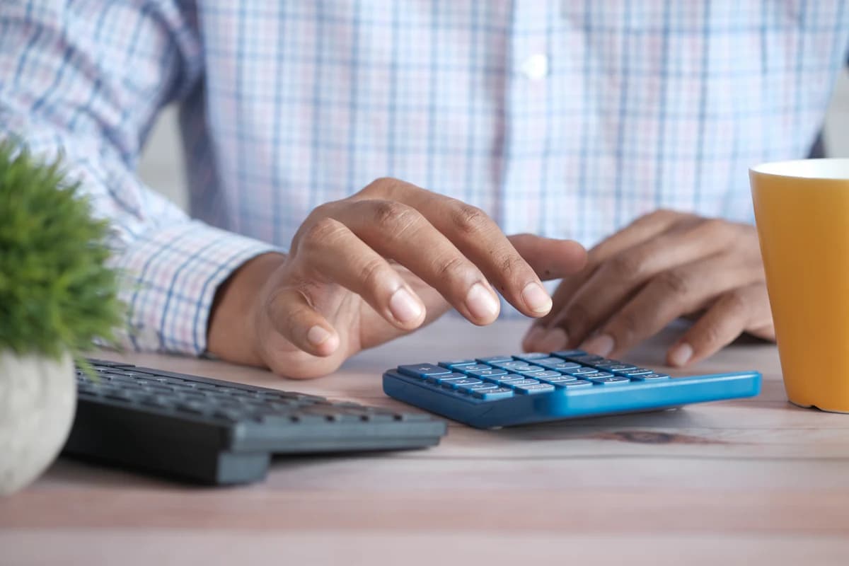 Someone working through bills at a desk with a calculator.
