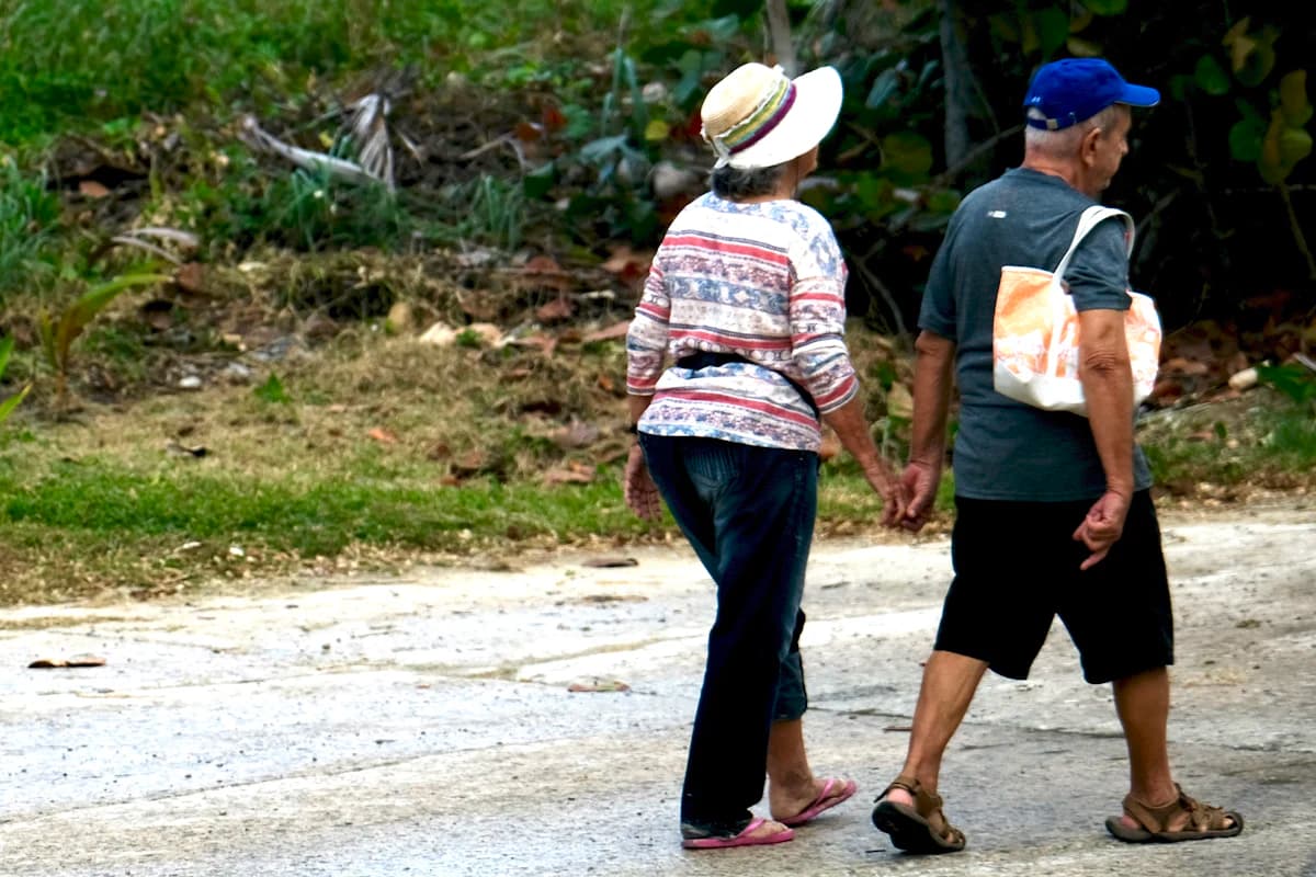 An older couple walking hand in hand outdoors.