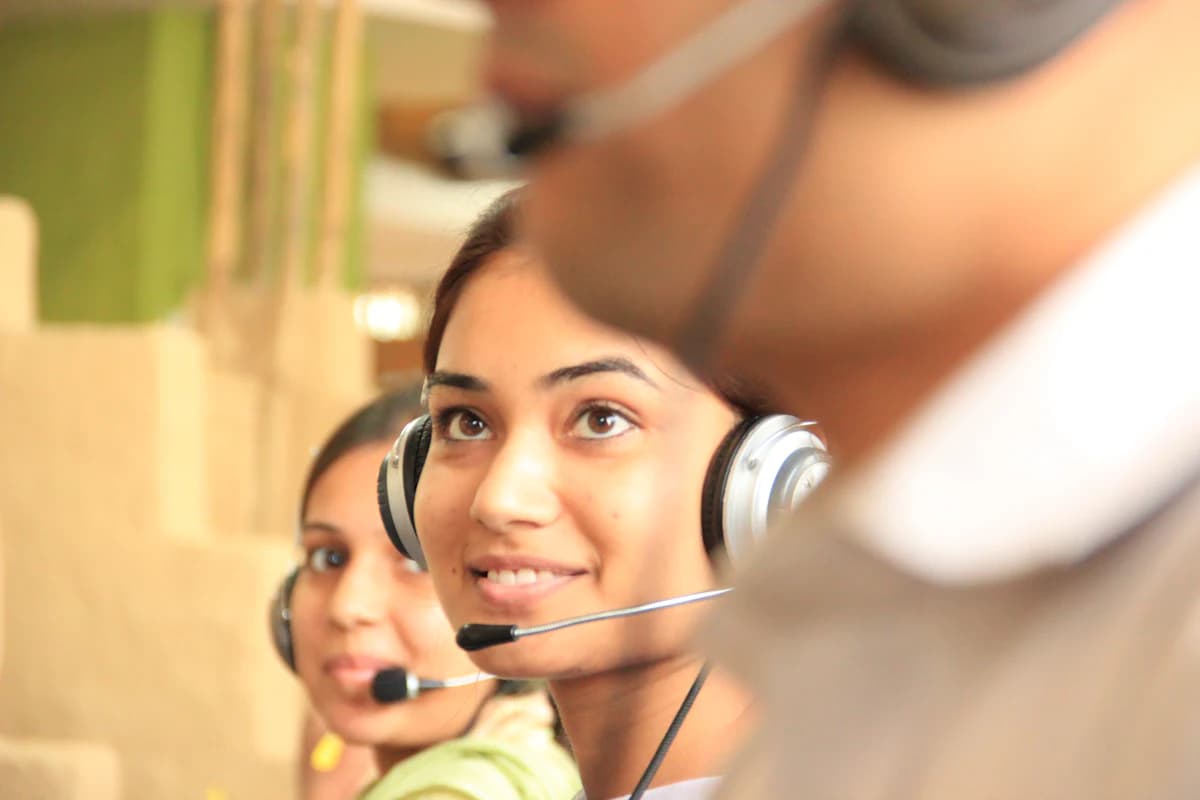 Two agents wearing headsets at their desks in a bright office, taking live calls.