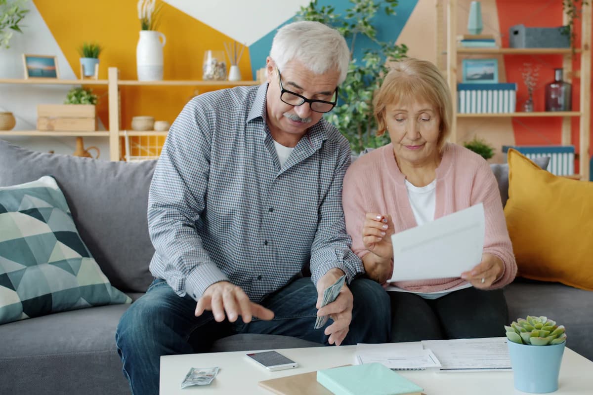 An older couple sitting together at home, going through paperwork.